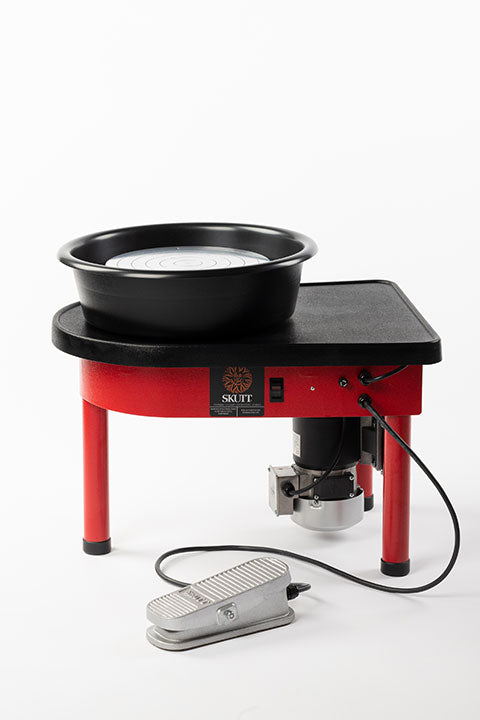 Red pottery wheel with a black basin and foot pedal, ideal for wheel throwing and ceramic projects.