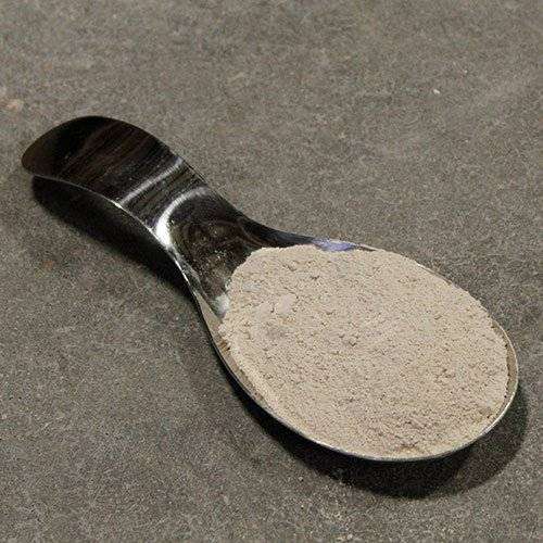 Close-up of a metal spoon filled with fine pottery clay, ideal for sculpture and ceramic projects.